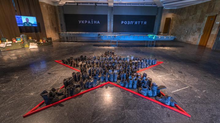 a large hall with a star shaped pile of military boots with a red outline in a museum inKyiv, Ukraine